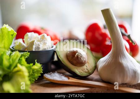 Healthy vegetables and fresh ingredients on wooden cutting board in front of bright kitchen window. Healthy nutrion concept for a spring diet. Close-up with space for text. Stock Photo