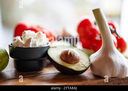 Healthy vegetables and fresh ingredients on wooden cutting board in front of bright kitchen window. Healthy nutrion concept for a spring diet. Close-up with space for text. Stock Photo
