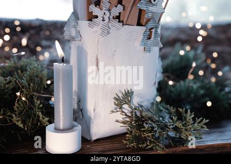 Homemade advent calendar made of cardboard. Small cardboard boxes in a white paper bag decorated on rustic wood. Sustainable christmas packaging. Background for a eco friendly christmas surprise. Stock Photo