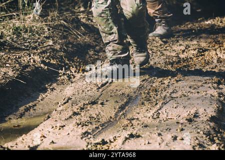 Brown military boots on mud and puddle Stock Photo