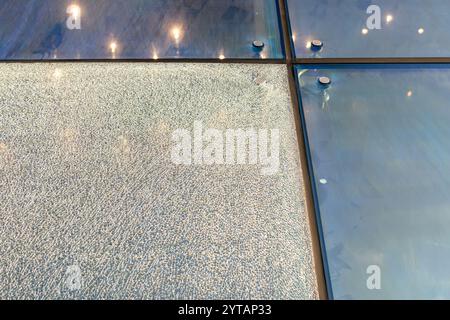 Shattered facade glass panel with visible cracks, no falling. Smart glass technology, damage control Stock Photo