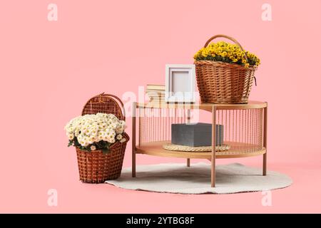 Coffee table, decor and basket with chrysanthemum flowers on pink background Stock Photo