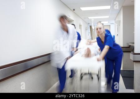 Doctor Rushing Patient In Medical team rushing patient on gurney through hospital corridor ...