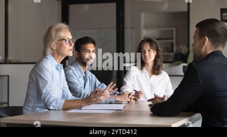 Group of professionals sit around conference table engaged in discussion Stock Photo
