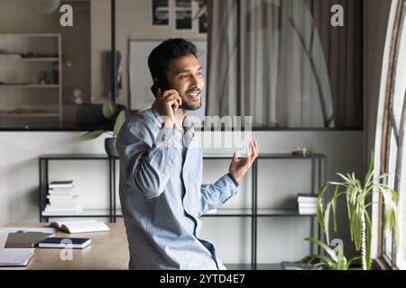 Young Indian businessman engaged in work-related discussion on smartphone Stock Photo