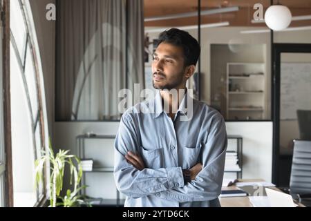 Indian business man standing with arms crossed with thoughtful expression Stock Photo