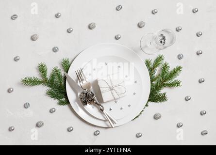 New Year table setting with gift in plates and silver decor on a white background. Christmas dinner. Top view, flat lay. Stock Photo