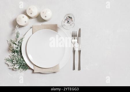 Christmas serving with empty white plate, candles and silverware on a white background. Beautiful New Year table setting with copy space. Top view, fl Stock Photo