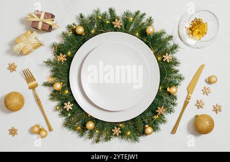 Christmas serving with empty plate and gold decorations on a white background. New Year party. Festive table setting for the new year. View from above Stock Photo