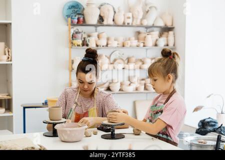 A mother and daughter create pottery together in a sunny art studio Stock Photo