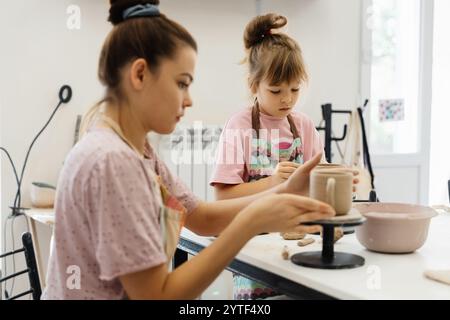 A mother and daughter creating pottery together at a sunny studio Stock Photo