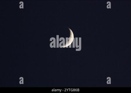 Crescent moon against a black night sky Stock Photo