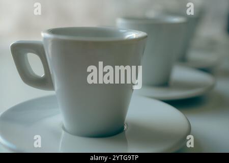Closeup of White coffee cups and saucers arranged on a white table Stock Photo