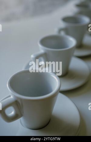 White coffee cups and saucers arranged on a white table Stock Photo