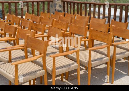 Group of empty wooden vintage chairs with rattan seats arranged in rows before an event. Many wooden outdoors armchairs. Public event furnishing Stock Photo