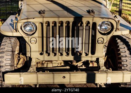 A jeep with a sunroof and a grill. The grill is covered in rust. The jeep is parked in the shade Stock Photo