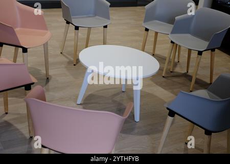 Empty chairs surrounding a small table ready for a coffee break in a communal area. Stock Photo