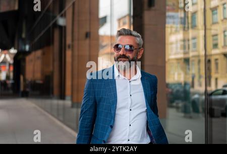 A happy mature man in elegant stylish clothes walking through the city street. Stock Photo