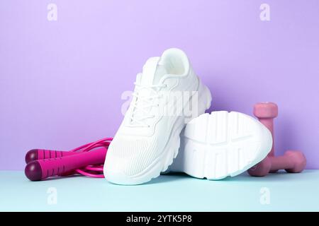 Pair of stylish white sneakers, dumbbells and skipping rope on color background Stock Photo