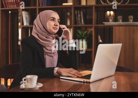 A young Muslim business woman talking on her phone while working at the office.  Stock Photo