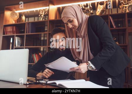 A business team of young man and Muslim woman working together on the project planning strategy in the modern office or Arabic college students study Stock Photo