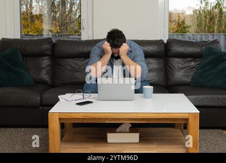Disappointed man working at home at laptop. Stock Photo