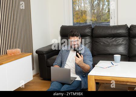 Angry stressed man having a phone call with a burnout face expression while working at the home office. Stock Photo