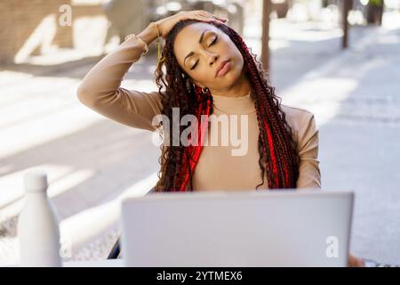 A Young Woman is Enjoying Relaxation While Working on a Laptop in a Modern Outdoor Environment Stock Photo