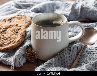 Steaming cup of coffee and blanket with cookies on a wooden table Stock Photo