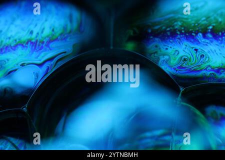 Bright rainbow reflection of liquid in macro, water forms on black background, surrealistic background, fantastic smooth movement Stock Photo