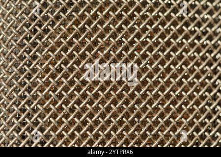 Macro view of a metallic mesh or grid. Mesh consists of interwoven metal wires forming a crisscross pattern, creating a textured and detailed surface. Stock Photo
