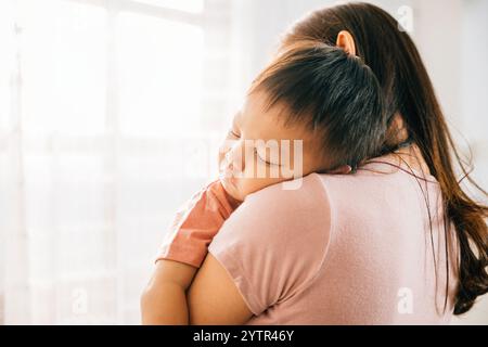 A tender loving biracial mother cradles her small sleeping newborn in her arms Stock Photo