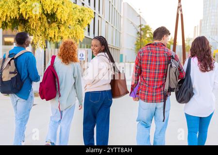 Group of diverse students walking together outdoors with backpacks Stock Photo