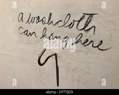 A piece of art in the Danish Museum of Art and Design in Copenhagen, Sweden: words handwritten on a white wall that say a washcloth can hang here Stock Photo