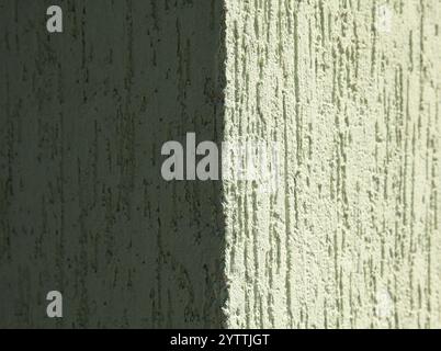 Green faded wall texture, background. Decorated surface in rough plaster. The corner of a wall or building. Old, pale, green backdrop Stock Photo