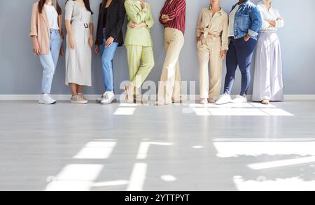 Cropped portrait of faceless young diverse women group standing confidently on gray wall background Stock Photo