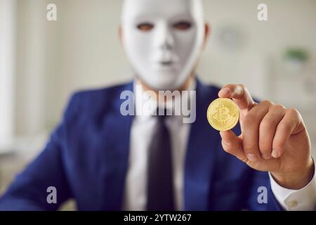Bitcoin in hand of masked secret man, cryptocurrency scam, financial criminal of digital wallet Stock Photo