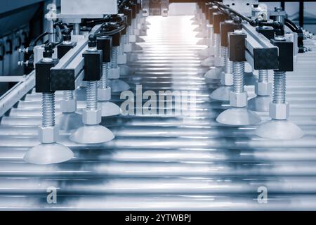 A conveyor belt with a machine that has a white object on it. The conveyor belt is long and it is made of metal Stock Photo