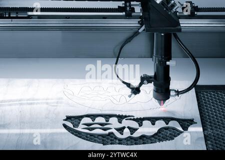 A laser cutter is cutting a design into a piece of wood. The design is a flower Stock Photo