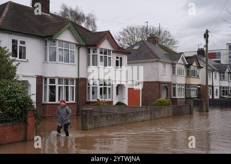 A person walks through floodwater in Greyfriars Avenue in Hereford, Herefordshire, after Storm Darragh hit the UK and Ireland. Picture date: Sunday December 8, 2024. Stock Photo