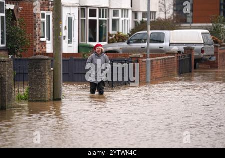 A person walks through floodwater in Greyfriars Avenue in Hereford, Herefordshire, after Storm Darragh hit the UK and Ireland. Picture date: Sunday December 8, 2024. Stock Photo