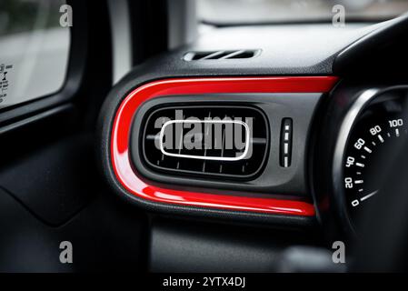 Leftmost A/C vent in car dashboard - deflector of air conditioning system. Car interior with red trim stripe. Modern car with climate control. Stock Photo