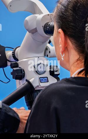A woman looks into the binoculars of a dental microscope Stock Photo