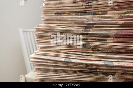 Tall stack of business newspapers neatly arranged on a table, showcasing printed articles and headlines Stock Photo