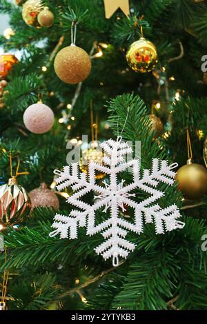 Closed up silver glitter snowflake ornament on white Christmas tree, selective focus and blurred background Stock Photo