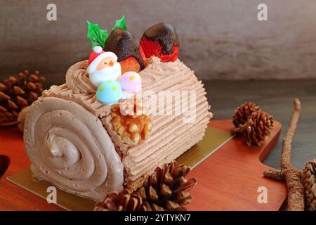 Buche de Noel on Wooden Breadboard Surrounded with Natural Dried Pinecones Stock Photo