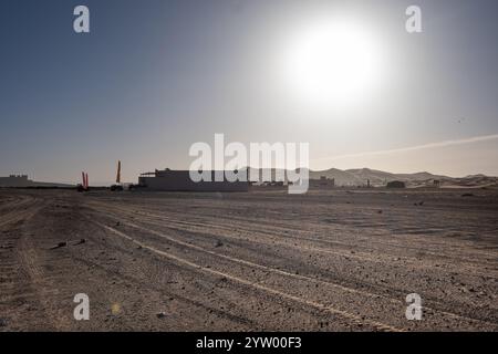 Marks of motorcycles and off-road vehicles on a plain at the edge of the dunes of the Merzouga desert in the Sahara of Morocco. There are small low ho Stock Photo