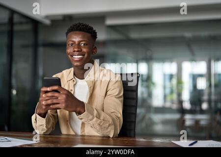 Portrait of happy African business man using smartphone working sitting at desk. Stock Photo