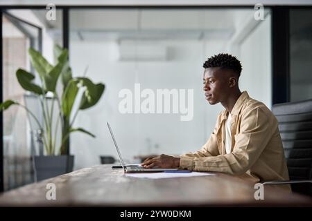 Busy professional African young businessman using laptop working at office desk. Stock Photo