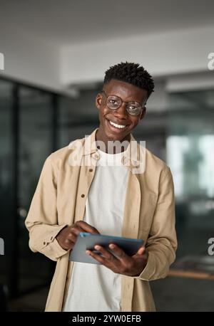 Smiling busy young Black business man using tablet standing in office. Stock Photo
